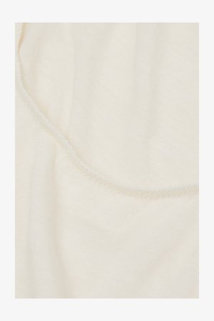 Cremefarbener Stoff mit weicher, glatter Textur und einem dezenten Glanz. Die Kanten zeigen eine zarte, feine Naht.