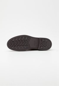 Gummi-Sohlen mit einer einheitlichen schwarzen Farbe, ausgestattet mit einem Zickzackprofil für Traktion und Langlebigkeit. Glatte Textur mit abgerundeten Kanten.