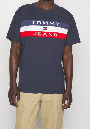 T-shirt en coton marine avec de larges rayures horizontales bleu, blanc et rouge, arborant "TOMMY JEANS" en évidence sur la poitrine.