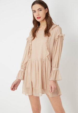 Vestido beige claro con detalles de volantes en el escote y las mangas, mangas largas y un dobladillo acampanado. Fabricado en una tela texturizada.