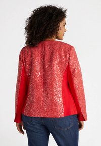 Röd jacka med en rygg dekorerad med paljetter, fasta röda ärmar och en öppen skärning. Texturerad, livlig yta designad för en avslappnad passform.