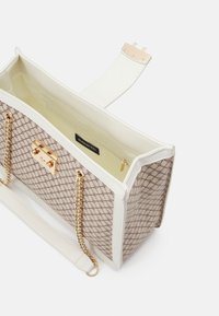 Strukturovaná kabelka s béžovým geometrickým vzorem, bílými akcenty, zlatými kovovými prvky a řetízkovým popruhem. Interiér obsahuje kapsu na zip.