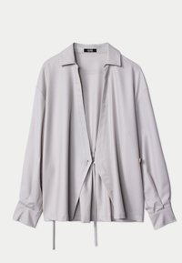 Grå blus med lång ärm, krage, öppen framkant och dragsko i midjan. Har en mjuk textur och lös passform.