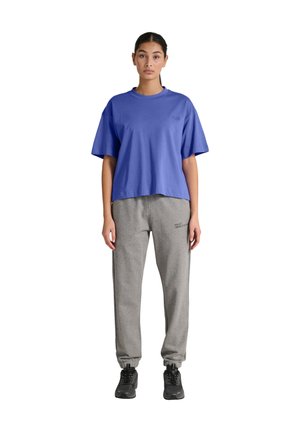 Kungligt blå oversized t-shirt med rund halsringning, kombinerad med ljusgrå avsmalnande sweatpants med logodetalj. Svarta träningsskor.