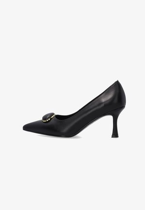 Zwarte leren pump met spits toelopende neus, lage naaldhak en een ronde zwarte gesp met een dunne gouden rand aan de voorkant.