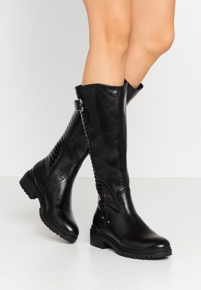 Bottes noires en cuir montantes avec un dos texturé et une fermeture éclair. Présentent un petit talon carré et un détail de boucle ajustable.