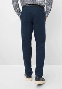 Pantaloni di cotone blu navy con taglio dritto, tasche posteriori con chiusura a bottone e una texture liscia, abbinati a calzature casual nere.