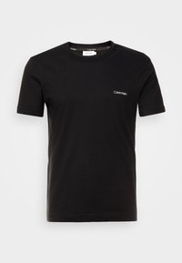 Svart bomulls t-shirt med rund halsringning och korta ärmar. Litet vitt "Calvin Klein"-logotyp på vänster bröst.