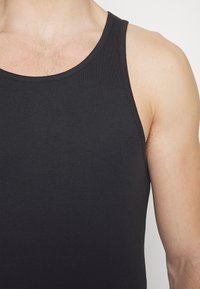 Schwarzes Tanktop aus glattem Stoff, mit klassischem Rundhalsausschnitt und weiten Armausschnitten, geeignet für legere Outfits oder zum Layering.