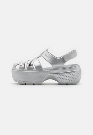 Silver platform sandals with an open design, featuring thick straps, pyramid studs, and a textured sole for grip.