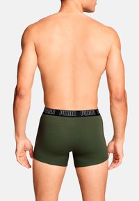 Männer Boxershorts in Grün mit einem schwarzen PUMA-Logo-Bund; figurbetontes Design, glatte Textur und mittellange Länge bis zum Oberschenkel.