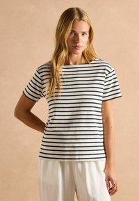 Ribakiri tee-shirt kreemjas ja tumesinises toonis, lühikesed varrukad, ümar kaelus, mugav lõige, valmistatud pehmest puuvillakangast.