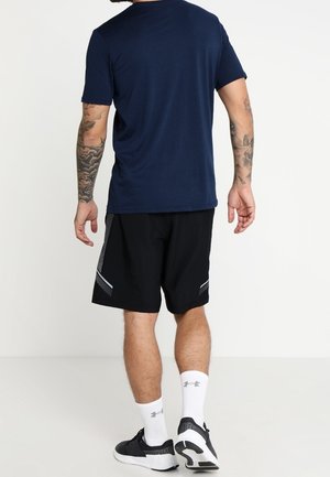 Mörkblå kortärmad skjorta kombinerad med svarta shorts med reflekterande detaljer. Outfiten avslutas med vita strumpor och svarta sportskor.