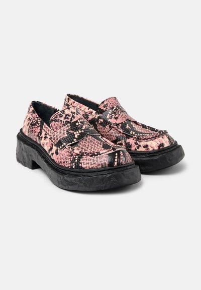 Pink and black snake-print slip-on shoes, featuring a thick black sole, textured upper, and contrasting black straps across the vamp.