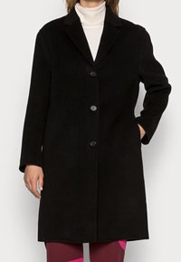 Cappotto in lana nero con colletto a risvolto, chiusura con cinque bottoni e maniche lunghe. Tessuto liscio, design fino al ginocchio e tasche laterali.