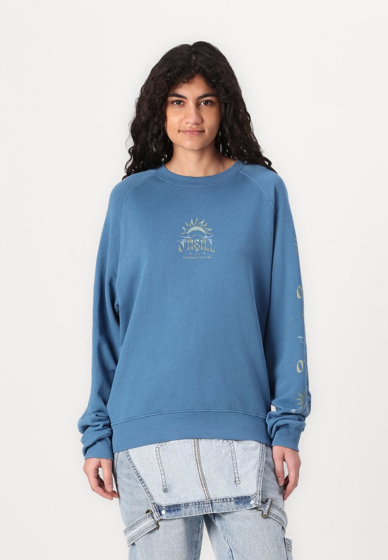 Sudadera azul con cuello redondo y mangas raglán. Presenta un gráfico de sol en la parte delantera y texto impreso en las mangas. Textura suave de algodón.
