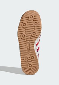 Sneakersula med en texturerad gummibas, med ett mönster av cirkulära och räfflade designer i beige och vitt, med färgglada accenter.