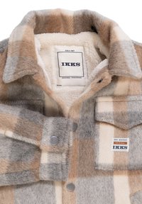 Camicia di lana con bottoni in grigio, beige e crema a quadri, con un interno morbido, tasche frontali e un'etichetta del marchio all'interno del colletto.