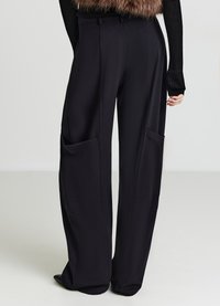 Schwarze weit geschnittene Hose aus glattem Stoff, mit zwei großen aufgesetzten Taschen vorne und einem taillierten Bund, der eine strukturierte Silhouette verleiht.