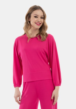 Maglietta fucsia a maniche lunghe con scollo arrotondato, caratterizzata da un dettaglio dorato al collo. Realizzata in un tessuto morbido ed elasticizzato per garantire comfort.