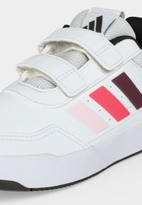 Λευκό αθλητικό παπούτσι με τρεις λουριά Velcro, πλέγμα γλώσσα και πλαϊνές ρίγες σε ανοιχτό ροζ, κόκκινο και σκούρο μωβ.