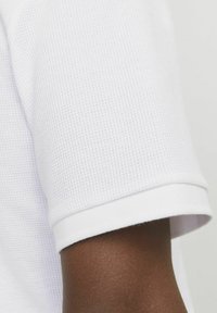 Polo shirt blanc à texture, à manches courtes, avec un col côtelé, présentant un motif à grid subtil et un design épuré et ajusté.