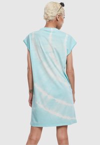 Svijetloplava tie-dye haljina s kratkim rukavima, labavog kroja i jednostavnim rubom. Tkanina izgleda mekano s glatkom teksturom i suptilnim bijelim uzorcima.