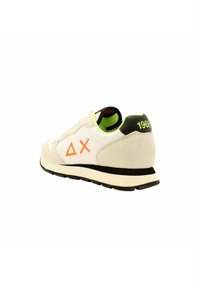 Baskets en suède et mesh blanc cassé avec détail logo orange, talon noir et accents vert fluo. Texture douce, forme classique de chaussure de course.