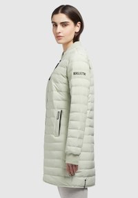 Jachetă puffer de culoare verde deschis, cu un design quilted orizontal, buzunare laterale și guler ribbat. Prezintă branding pe mâneca stângă.
