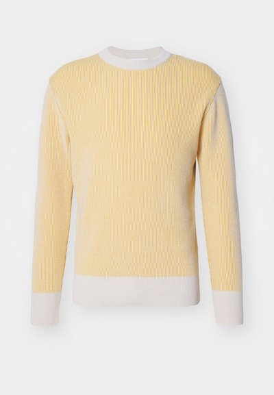 Ljusgul ribbad stickad tröja med långa ärmar och vit nederkant. Har en rundad halsringning och texturerad tyg.
