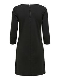 Abito nero al ginocchio con maniche a tre quarti e cerniera argentata visibile sulla scollatura posteriore.