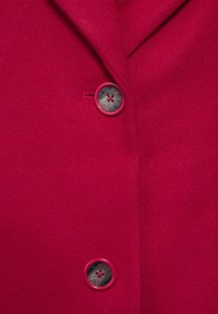 Abrigo de mezcla de lana rojo con solapas afiladas, que presenta un botón de plástico prominente en rojo y transparente con un detalle de patrón floral.