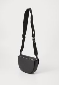 Borsa a tracolla nera con un design curvo, realizzata in materiale liscio. Presenta una tracolla in tessuto regolabile e chiusura con zip. Resistente e minimalista.
