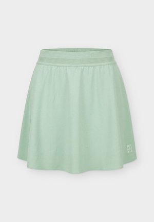 Heleheleroheline sportlik seelik laia elastse vöökoht ja väikese valge logoga alumises paremas nurgas, esitatud ühtlasel taustal.