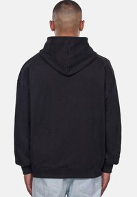 Sort hættetrøje med en stor, foret hætte og løs pasform. Har ribbet mansjetter og kant. Fremstillet af blødt bomuldsstof, minimalistisk design.