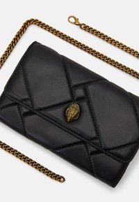 Black quilted leather clutch with gold-tone chain strap and decorative gold-tone clasp shaped like a textured bird head.