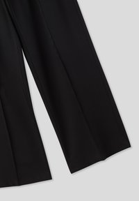 Pantaloni neri a gamba larga realizzati in tessuto morbido. Presentano una vita alta, linee pulite e nessun hardware o motivo visibile.