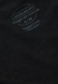 Černá látka s měkkou texturou, která obsahuje potištěný bílý text. Detaily zahrnují "intimissimi," "Ultralight with Cashmere" a "Navrženo v Itálii."