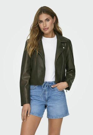 Chaqueta de cuero verde oliva recortada con cierre de cremallera, cuello de solapa y hombreras, usada sobre una camiseta blanca y pantalones cortos azules.