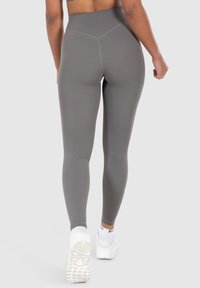 Leggings a vita alta, aderiscono alla figura e sono realizzati in morbido tessuto grigio opaco. Presentano un design senza cuciture con dettagli di cucitura sottili.