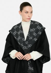 Cappotto avvolgente nero con un colletto grigio a motivo, caratterizzato da un sottile design del logo. Il tessuto testurizzato e le maniche larghe esaltano la silhouette.