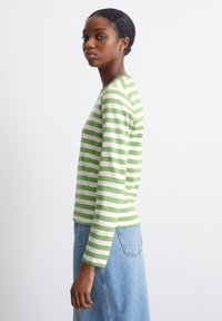 Groen-wit gestreepte lange mouwen top met een ronde halslijn, gemaakt van zachte stof, gecombineerd met een denim rok. Eenvoudig, aansluitend ontwerp.