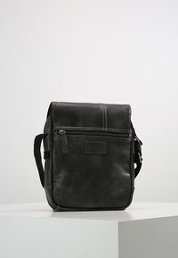 Borsa in pelle nera con patta, tasca frontale con zip, tracolla regolabile e cuciture a contrasto. Design compatto e rettangolare con una texture liscia.