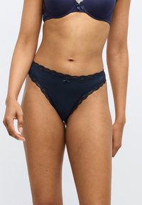 Culotte bleu marine bordée de dentelle avec des bords en forme de festons et un petit nœud à l'avant, confectionnée dans un tissu doux et extensible.