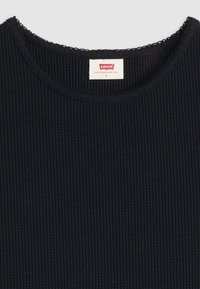 Juodas ribotas marškinėliai su apvaliu iškirpimu ir banguotu apdaila. Viduje etiketė su užrašu "Levi's", dydis S. Audinys atrodo tekstūruotas ir minkštas.