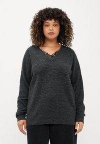 Suéter cinza escuro com decote em V, apresentando delicados detalhes em renda preta, mangas longas e um corte descontraído. Textura suave e design minimalista.