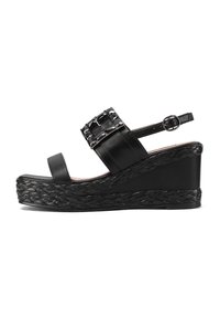 Sandalo con zeppa nera, suola intrecciata, cinturino alla caviglia e parte superiore texturizzata con borchie decorative. Pelle liscia e accenti texturizzati.
