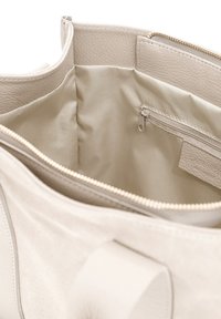 Borsa beige con un esterno morbido e testurizzato e una fodera interna liscia. Presenta una chiusura con zip e una tasca interna con zip.
