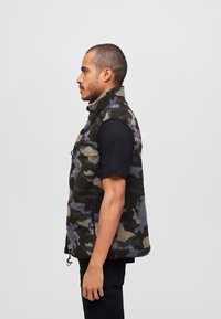 Fleeceväst i kamouflagemönster med nyanser av svart, grått och blått; har hög krage och dragkedjefickor; avslappnad passform.