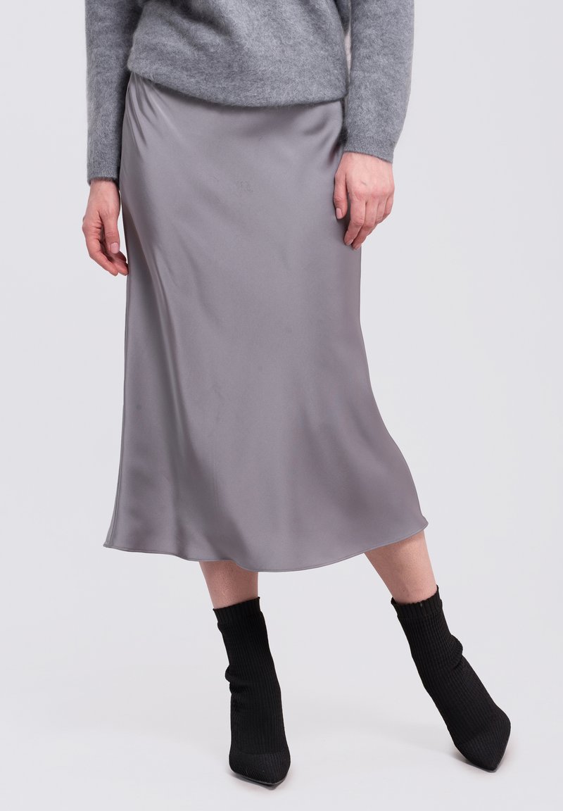 Zijdegrijze midi-jurk met een soepele textuur, lichte glans en een vloeiende silhouet. Gecombineerd met geribbelde zwarte enkellaarzen.